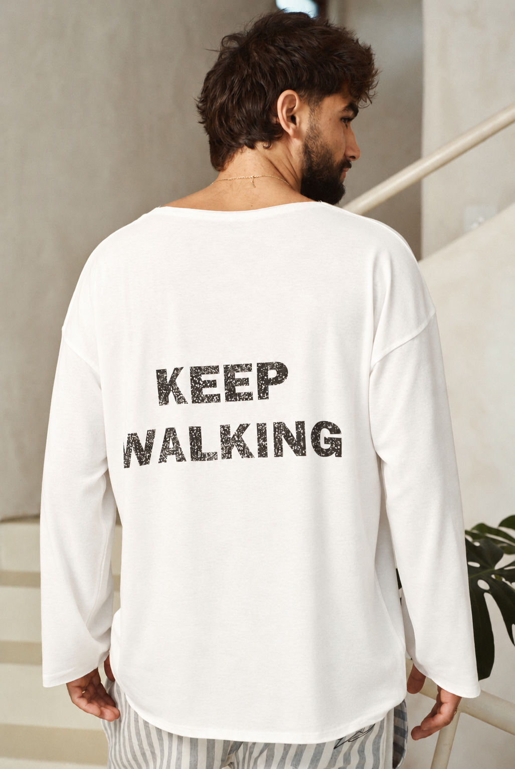 דוגמן מציג את גב חולצת KEEP WALKING הלבנה