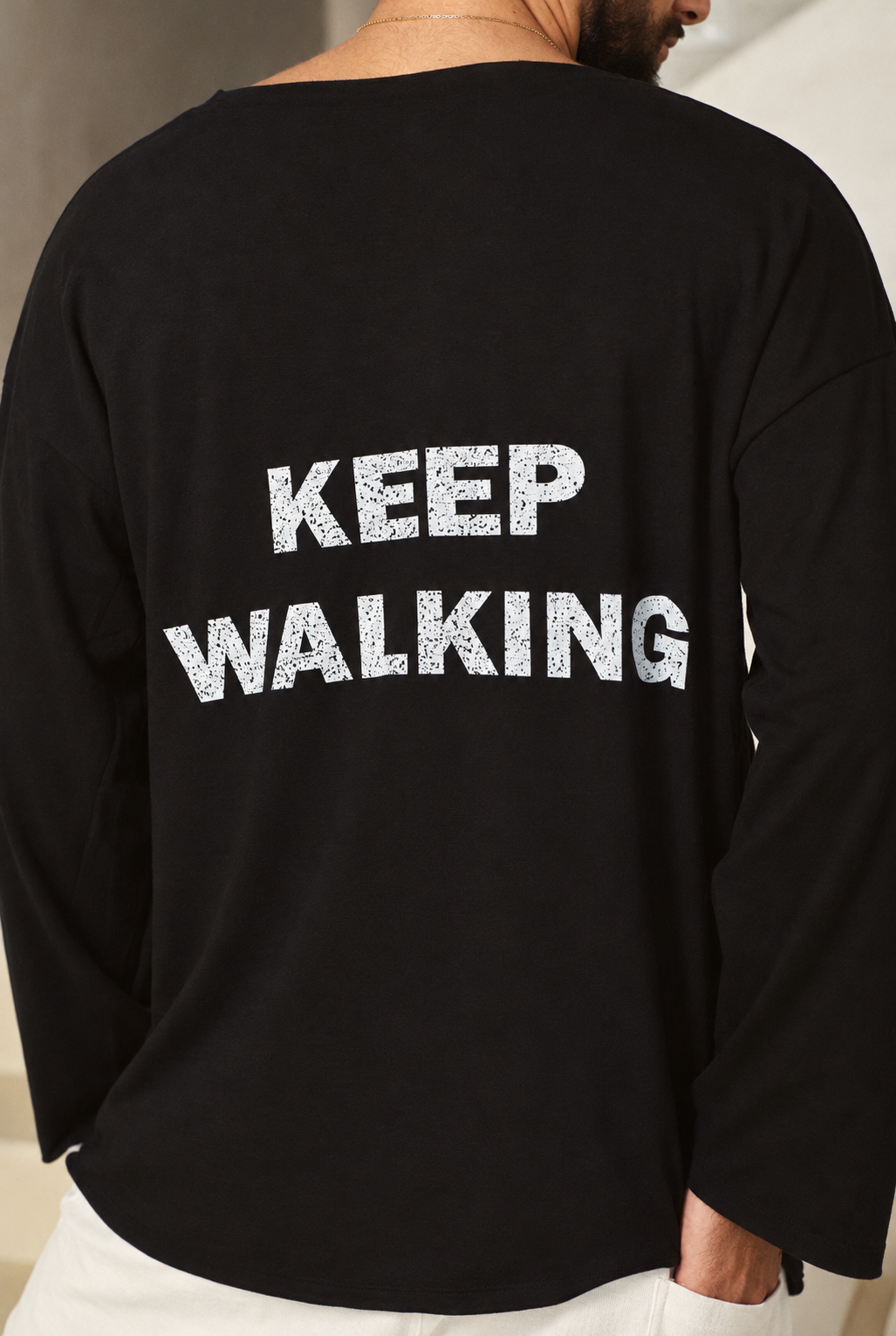 תקריב הכיתוב הלבן KEEP WALKING בגב חולצה שחורה