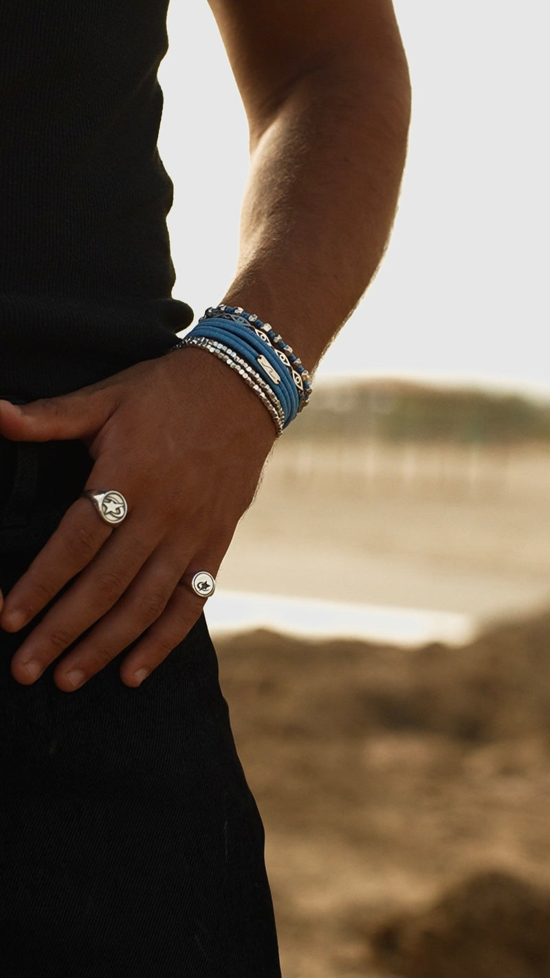 Person wearing multiple bracelets and a ring with a blurred background