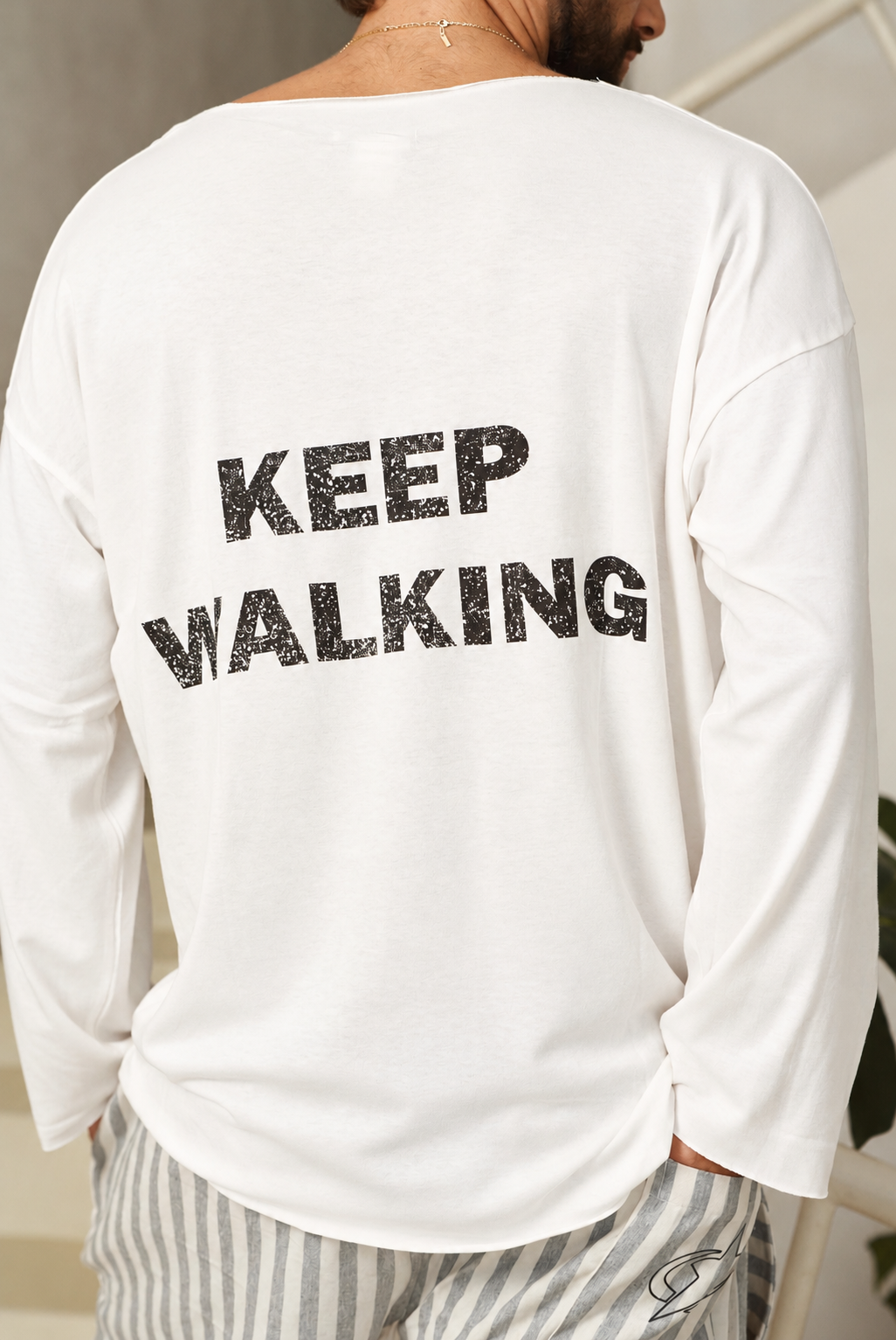תקריב הכיתוב השחור KEEP WALKING בגב חולצה לבנה
